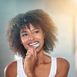 Woman looking in mirror and brushing her teeth