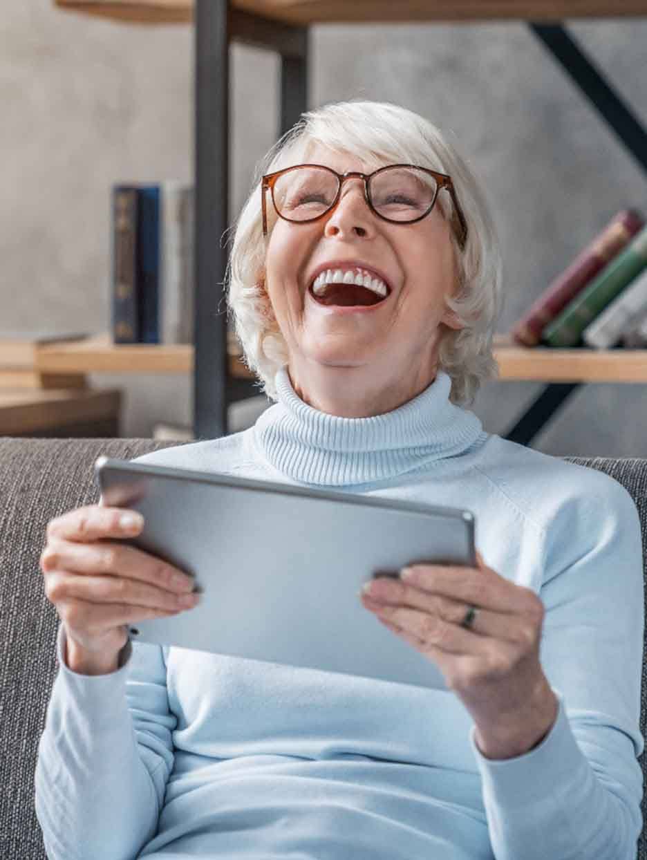 Senior woman looking at tablet and laughing