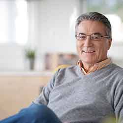 Senior man smiling and sitting on orange chair