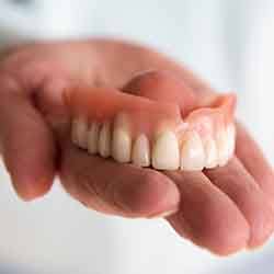 Close-up of hand holding dentures in Cary, NC