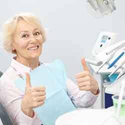 Senior woman in dental chair giving double thumbs up