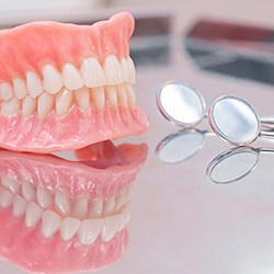 Dentures in Cary, NC sitting on table with dental mirror