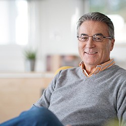 Senior man in grey shirt sitting on couch