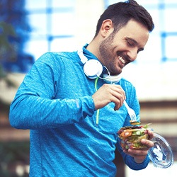 Man with headphones eating a salad