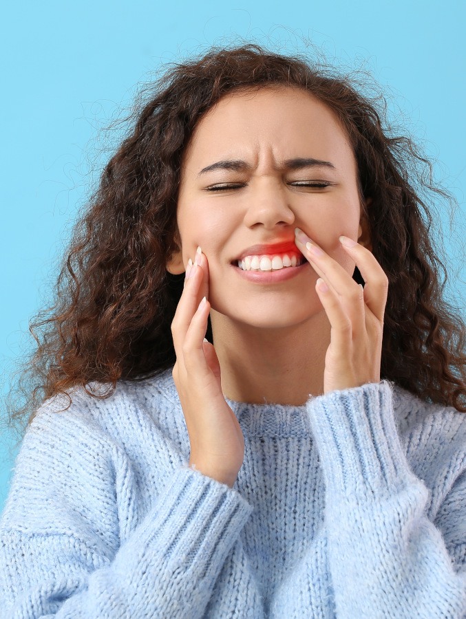 Woman in sweater in pain from inflamed gums