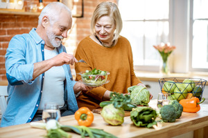 Two seniors with one holding a salad