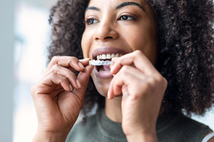 Woman opening mouth to put in Invisalign aligner