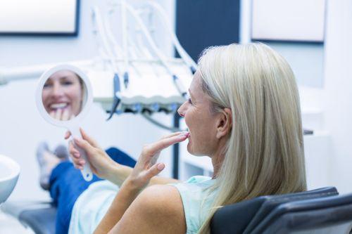 blonde woman sitting in dentist exam chair | dental implants cary nc